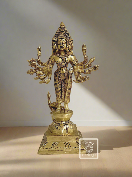 A brass statue of Lord Kartikeya with six faces and multiple arms, holding various objects, with a small peacock behind it.