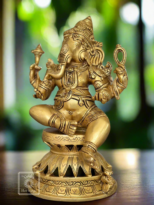 A bronze statue of Ganesha sitting in a meditation pose with a decorative base, placed on a wooden surface.