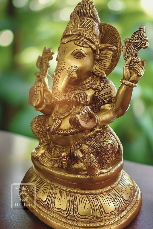 A bronze-colored brass statue of Lord Ganesha, showing him in a sitting pose with his usual attributes like a elephant head, holding a Modak , and wearing a turban.