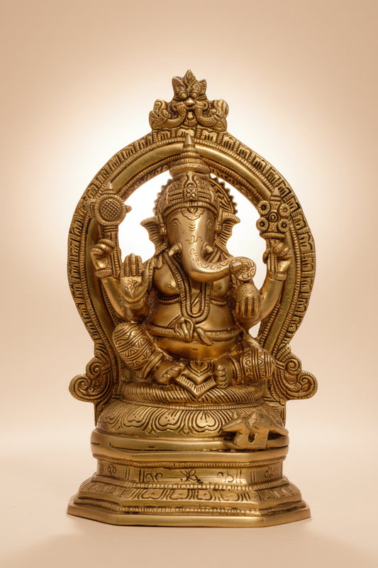 A brass statue of the Hindu god Ganesha with a decorative frame(Prabhavali), showcasing intricate designs and details.