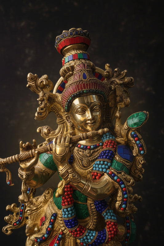 An ornate golden statue of a deity adorned with red, blue, and green beaded details, set against a dark textured background.