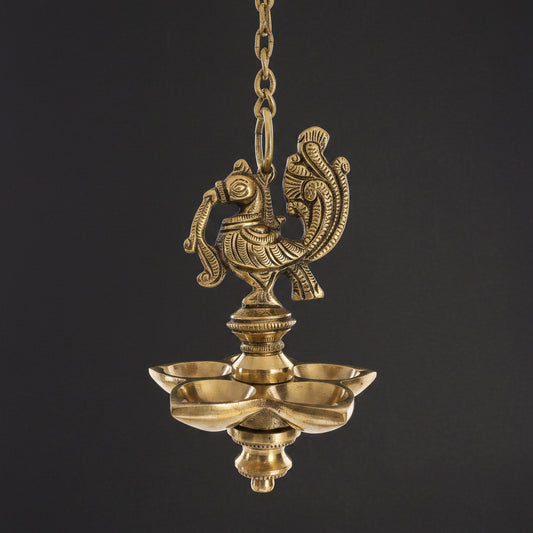 An ornate brass hanging oil lamp with a decorative Peacock figure on top and five shallow cup holders.