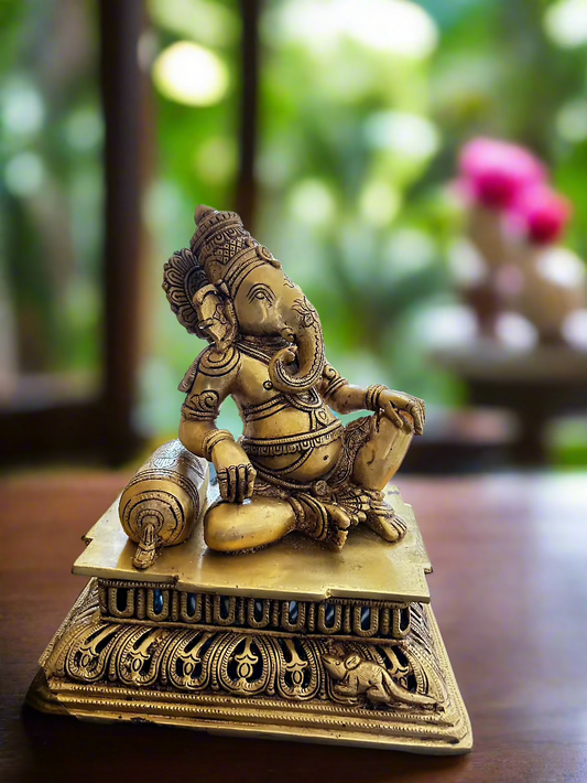 A bronze Ganesha statue sitting on a decorative base(Asana) , with intricate detailing, 