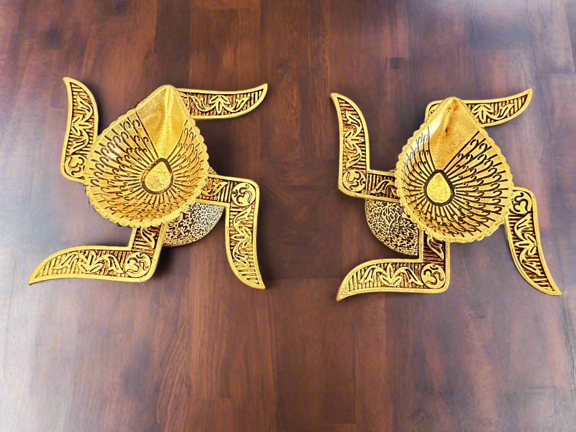 Two gold-colored brass oil lamps with swastika designs 