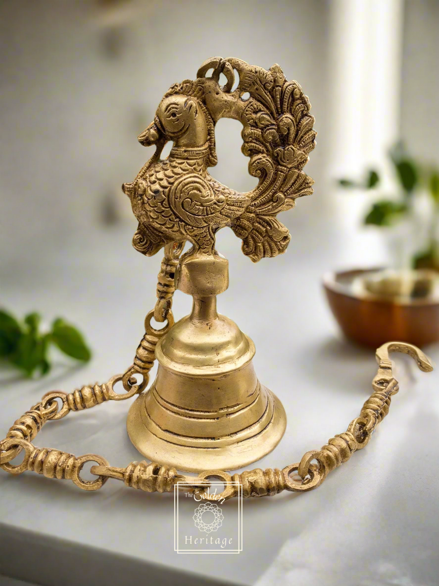 A solid brass peacock bell with a chain, featuring intricate detailing and a glossy finish.