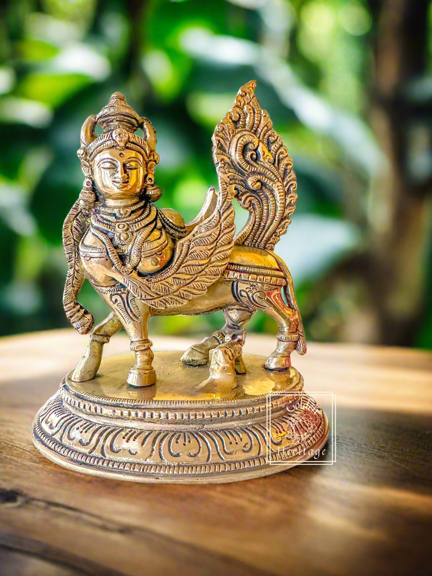 A brass statue of Kamdhenu, a figure with a decorative headdress and a cow's body.