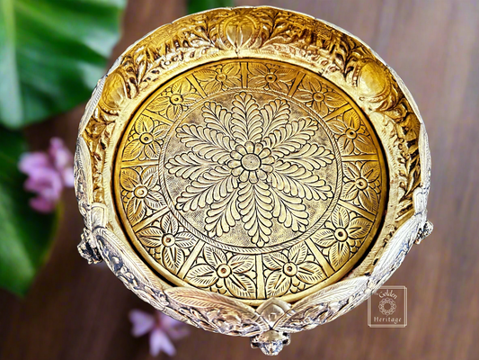 A decorative brass bowl with floral and animal (ganesha) patterns
