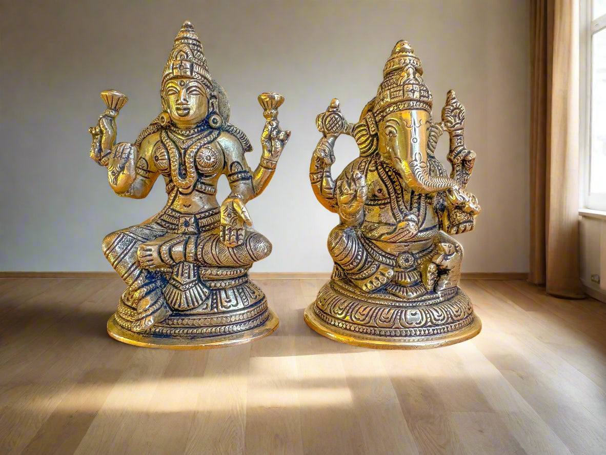 A set of two brass figurines, one representing Ganesha and the other representing Lakshmi, both with intricate detailing and seated positions.