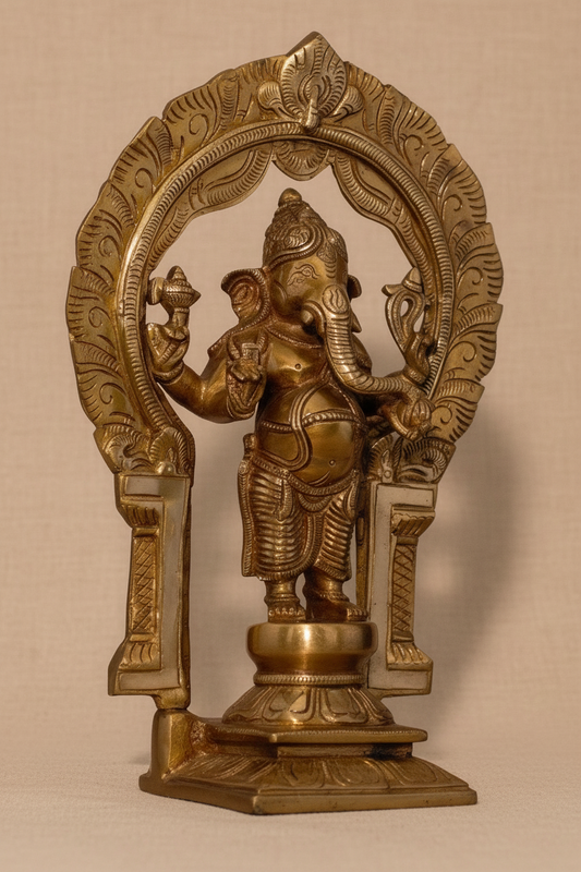 A brass statue of Lord Ganesha standing within an ornate arched halo, photographed against a plain beige fabric background.